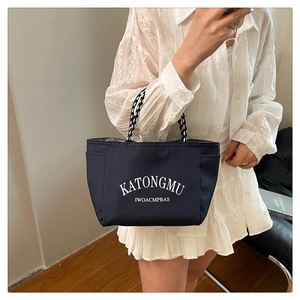 Detail of navy canvas tote with striped rope handles and white graphic lettering