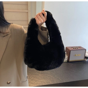 Close-up of black faux fur handbag held by model in a stylish indoor lifestyle setting