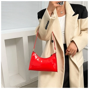 Détail du sac baguette en cuir verni rouge brillant avec une bandoulière fine