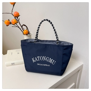 Detail of navy nylon tote bag featuring durable woven rope handles and side pocket