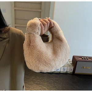 Detail of soft beige faux fur handbag held by model in a cozy lifestyle setting