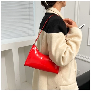Sac baguette en cuir verni rouge brillant porté à l'épaule dans un style épuré