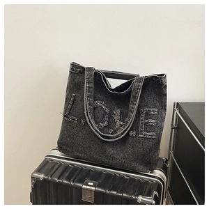 Detail shot of distressed black denim tote bag featuring vintage frayed LOVE letter patches