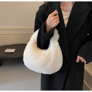 Close-up of white plush crescent faux fur handbag held by model in black coat
