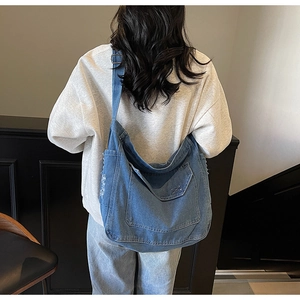 Gros plan du sac en jean bleu délavé avec détails effilochés et grande poche frontale