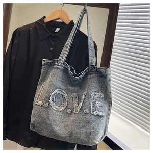 Detailed close-up of blue washed denim tote bag featuring white frayed L.O.V.E. letter design