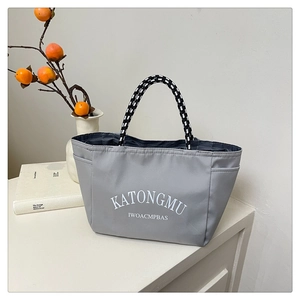 Detail view of grey fabric tote with decorative letters and woven rope handles