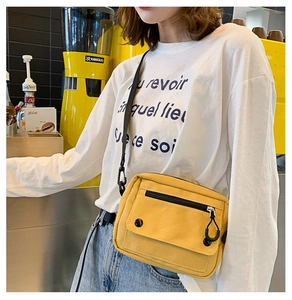 Detail of yellow canvas crossbody bag with multiple pockets worn in a cafe setting