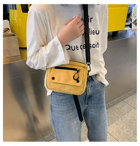 Detail shot of a yellow canvas crossbody bag featuring black zipper and wide shoulder strap