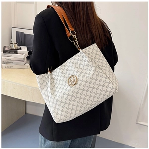 Detail of monogram printed tote bag with golden M logo and brown leather strap