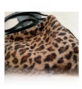 Detail of soft leopard print faux fur texture with elegant black shoulder strap