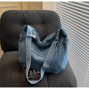 Détail du sac cabas en denim bleu avec grande poche à rabat et bandoulière ajustable