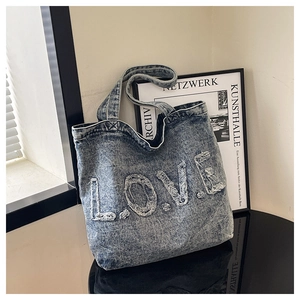 Detail of blue washed denim tote bag featuring frayed LOVE alphabet letter patches