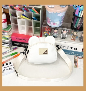 Detailed view of the white bear-eared crossbody bag with PU leather brand patch