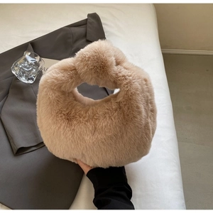 Detail view of a fluffy light brown plush handbag with a unique knotted handle design