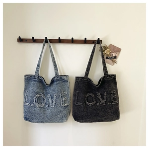 Detail of vintage washed denim tote bags with distressed LOVE letter embroidery and fringe edges