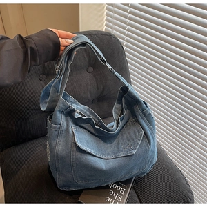 Détail du sac cabas en jean bleu avec bords usés et poche à rabat sur une chaise