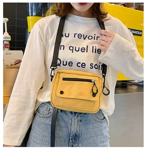 Detail of a bright yellow canvas crossbody bag featuring functional pockets and nylon strap