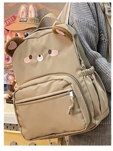 Detail of the cute khaki bear-shaped backpack with plush ears and embroidery