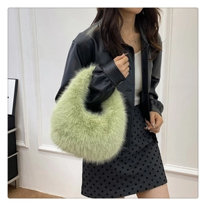 Détail d'un sac à main hobo en fausse fourrure vert clair porté par un mannequin stylé