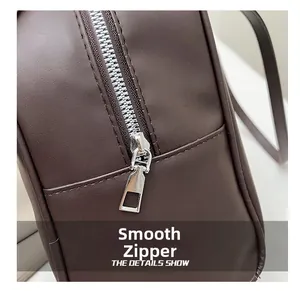 Close-up of smooth silver metal zipper on vintage dark brown faux leather tote bag