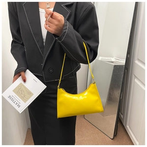 Détail du sac à bandoulière en cuir verni jaune vif brillant avec une texture lisse et chic