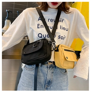Detail view of black and yellow canvas crossbody bags with adjustable straps on a model