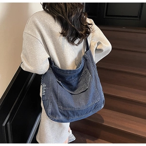 Détail du grand sac cabas en jean bleu foncé avec coutures contrastées et poche frontale