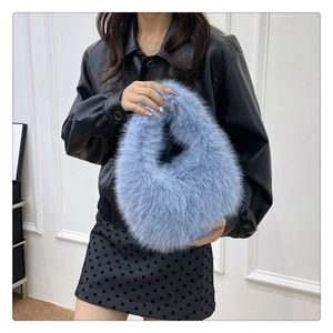 Détail de la texture douce du sac à main en fausse fourrure bleu clair sur veste noire