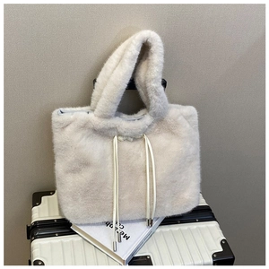 Close-up of white plush tote bag with thick handles and metal-tipped drawstring detail
