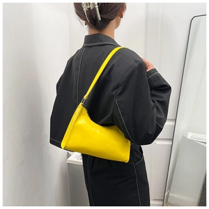 Gros plan d'un sac sous les aisselles en cuir verni jaune vif avec finition brillante élégante