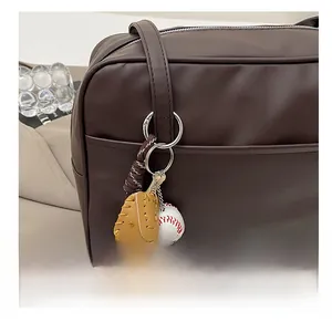 Detailed view of a vintage baseball glove and ball charm hanging on a brown leather bag