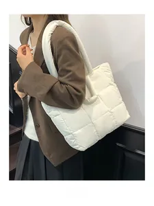 Side view of a white quilted down tote bag worn by a model in a brown blazer