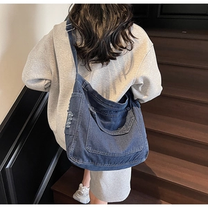 Détail du sac bandoulière en denim bleu délavé avec poche effilochée et bandoulière réglable