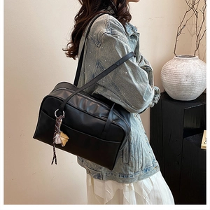 Detail of black Boston style shoulder bag with a creative baseball pendant on a model