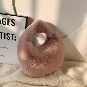 Detail of soft pink faux fur handbag placed on a white plush rug in cozy indoor lighting