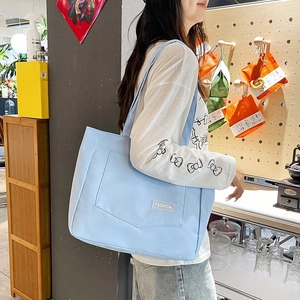 Light blue large nylon tote bag with front pocket and fashion label for casual style