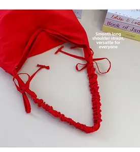 Detail view of red nylon cloud bag with ruched wide shoulder strap and side bow design