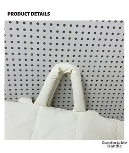 Close-up of soft padded handles on a white quilted puffer tote bag with fine stitching