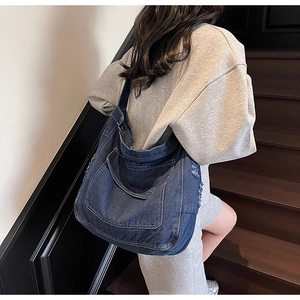 Détail du sac cabas en jean bleu délavé vintage avec bords effilochés et poche latérale