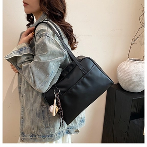 Model wearing a large black retro tote bag with baseball charm in minimalist interior