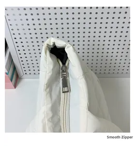 Detailed close-up of a smooth silver metal zipper on a white quilted cloud tote bag