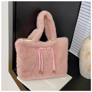 Detail of a plush pink tote bag featuring a decorative silk bow and metallic lace tips