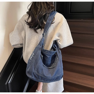 Sac fourre-tout en jean bleu foncé avec bandoulière réglable porté par un modèle