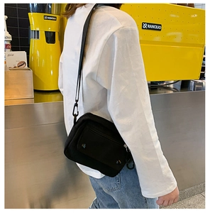 Detail view of black canvas crossbody bag with adjustable strap and front pocket