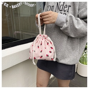 Detailansicht der rosa Cord-Beuteltasche mit Erdbeer-Stickerei in der Hand gehalten