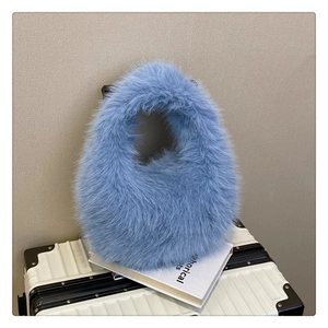 Gros plan du sac à main en peluche bleu clair sur une valise blanche vintage