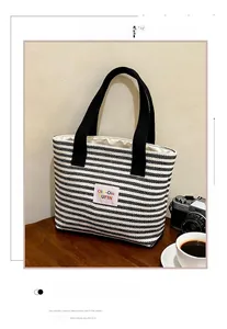 Close-up of striped canvas tote bag with pink PUFIN logo and retro camera prop