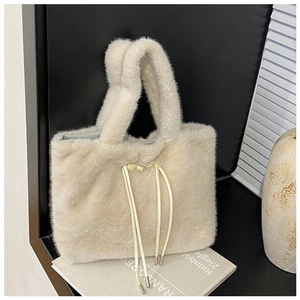 Detailed texture of cream plush tote bag with drawstring closure and silver metal tips