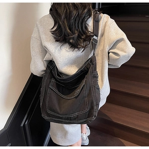 Détail du sac en toile noire avec coutures blanches contrastées et poche avant à rabat